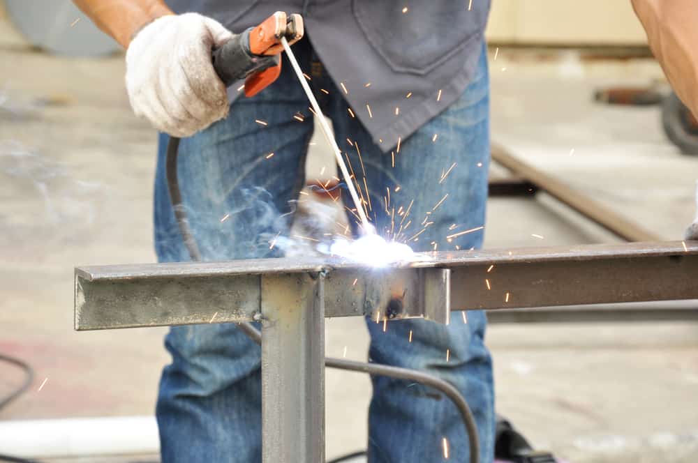  A worker using the metal fabrication technique of stick welding at a construction site.