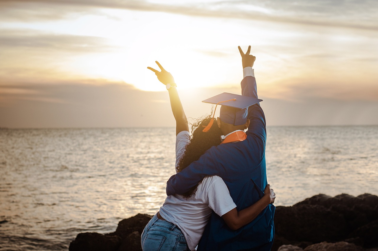 Graduates embracing at sunset by the water